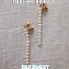 Pair of pearl drop earrings on a textured fabric background