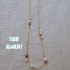Gold necklace with pearl and bead accents on beige fabric
