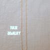 A thin gold necklace laid flat on a light fabric background.