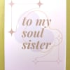 Greeting card reading 'to my soul sister' in tan script with pastel shapes and star accents.