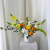 Yellow, white, and orange flowers in a white vase