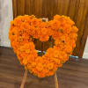 Heart-shaped marigold floral wreath on a wooden stand
