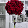 Tall bouquet of red roses in a clear vase with dark calla lilies