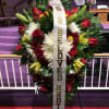 Large funeral wreath of red, white, and yellow flowers with a memorial ribbon