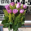 Pink roses arranged in a clear glass vase with yellow filler flowers