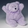 Soft lavender teddy bear with a checked bow sitting upright.
