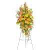 Tall standing spray of yellow sunflowers and orange roses with pink snapdragons on a metal easel
