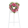 Heart-shaped wreath of pink flowers on a white easel stand