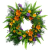 Green fern wreath with orange lilies, yellow roses, and purple flowers