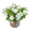Low arrangement of white roses and stock in a clear glass bowl vase with curly branches in the water