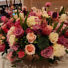 Low centerpiece of pink, purple, peach, and white roses with tulips and mixed blooms in a round bowl vase.