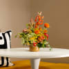 Colorful mixed flower arrangement in a gold vase on a white table