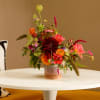 Colorful mixed flower arrangement in a low glass vase on a white table