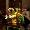 Colorful mixed flower arrangement in a yellow vase on a counter