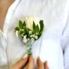White rose boutonniere with baby's breath and green leaves