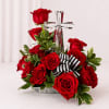 Red roses arranged around a clear glass cross with a striped ribbon