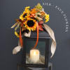 Silk sunflower arrangement on a black lantern with a lit candle inside