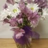 White daisies and purple alstroemeria in a glass vase with a purple ribbon