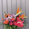 Tropical bouquet with orchids, roses, anthurium, and bird of paradise in a glass vase