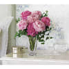Pink peony bouquet in a clear glass vase on a table