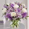 Bouquet of white roses and purple flowers in a clear glass vase
