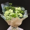 Green and white bouquet wrapped in beige paper with a ribbon