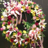 Heart-shaped floral wreath with pink lilies, roses, and ribbons