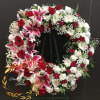 Heart-shaped floral wreath with red roses, pink lilies, and white flowers