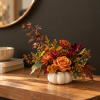 Autumn floral arrangement in a white pumpkin vase with orange and burgundy blooms