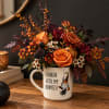 Orange and burgundy floral arrangement in a mug with a gnome design