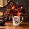 Halloween floral arrangement in a skull-print mug with orange and burgundy flowers
