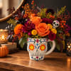 Orange and magenta flowers in a decorated skull mug vase