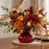 Autumn bouquet in a red glass vase with orange and burgundy flowers