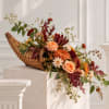 Autumn floral arrangement in a woven cornucopia basket with peach and orange blooms