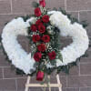 Heart-shaped white floral wreath with red roses on an easel