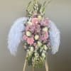 Pink and white floral standing spray with feathered white wings