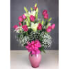 Pink roses and white lilies in a pink vase with a ribbon