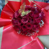 Bouquet of deep pink roses wrapped in bright red paper with a butterfly topper