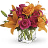 Pink roses and orange lilies arranged in a clear glass vase