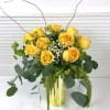 Yellow roses in a gold vase with trailing greenery