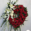 Heart-shaped floral wreath with red carnations and white lilies on an easel