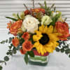 Square clear vase filled with sunflowers, roses, spray roses, alstroemerias and mix
