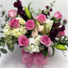 Pink and white flower arrangement in a pink box with a bow