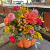 Mixed bouquet in a pumpkin-shaped container with pink, orange, and yellow flowers