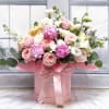 Pink and white roses in a pink hat box with a ribbon