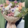 Large bouquet of pink, white, and peach flowers wrapped in patterned paper