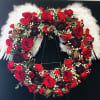 Heart-shaped floral wreath with red roses and white feathers