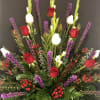 Tall arrangement of red and white roses with purple spikes in a decorative vase
