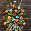 Tall floral spray with orange roses and blue accents on a stand