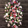 Large standing floral spray with pink lilies, red roses, and purple blooms